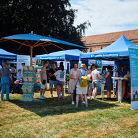 Foto: Personen stehen vor blauen Informationszelten auf einer Universitätsveranstaltung im Freien. Die Zelte sind mit Schildern wie 'Naturwissenschaftliche Studiengänge' und 'Allgemeine Studienberatung' beschriftet. Ein Plakat informiert über 'Zentrale Studienberatung'.