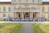 Foto: Eine große Gruppe von Personen steht vor dem Schloss Hohenheim. Das historische Gebäude mit symmetrischem Design und Säulen bildet den Hintergrund. Die Personen sind in mehreren Reihen aufgestellt.