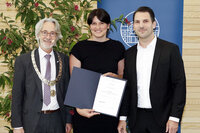 Foto: Drei Personen stehen vor einem Hintergrund mit Pflanzen und einem Banner der Universität Hohenheim. Eine Person hält eine Urkunde mit der Aufschrift 'HUTTER Young Researcher Paper Award 2023'.
